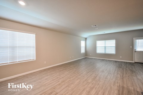 the living room of an empty house with wood flooring and windows