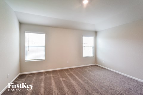 the spacious living room with carpeting and two windows
