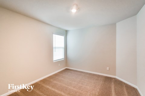 a bedroom with white walls and carpet and a window