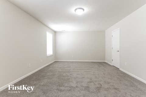 the spacious living room with carpet and a door to the bedroom