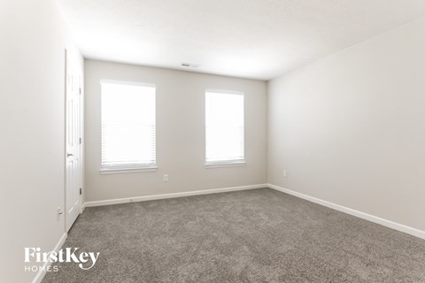 a bedroom with carpet and three windows