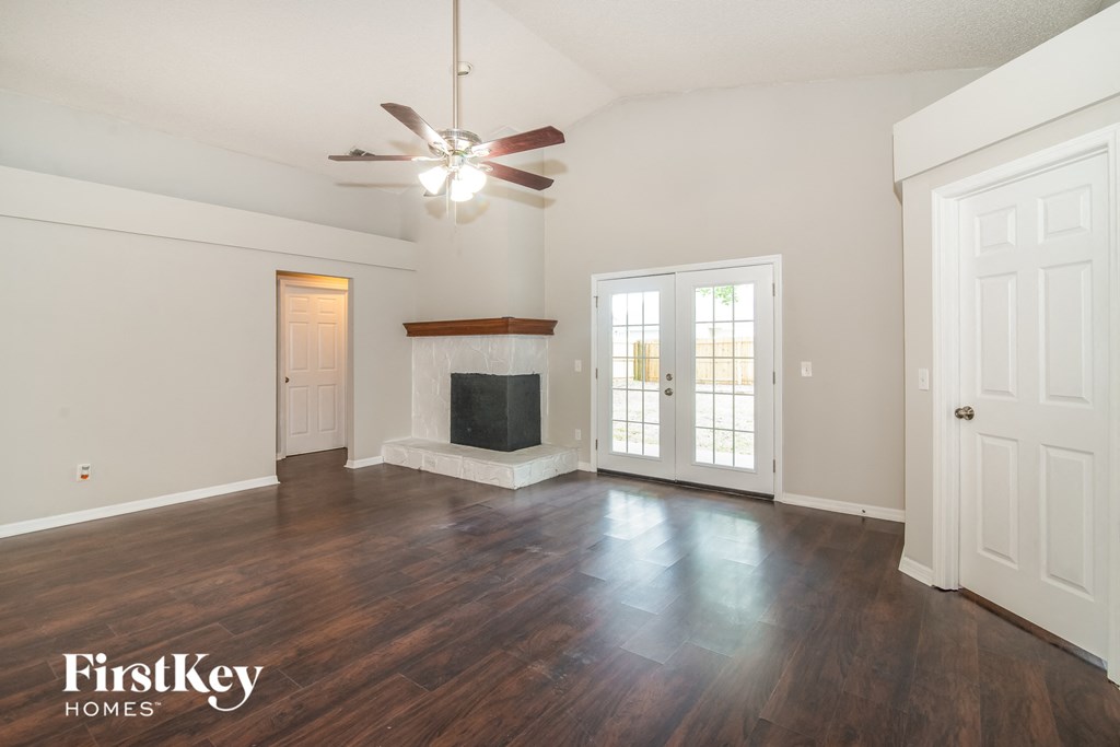 an empty living room with a fireplace and a ceiling fan