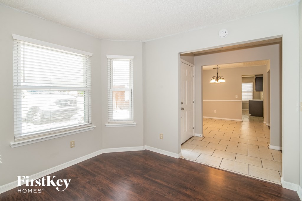 the living room and dining room of an empty house with wood flooring and windows