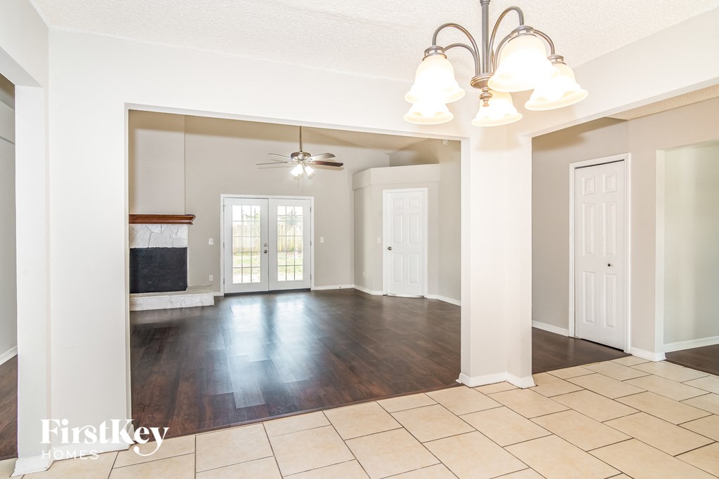 an empty living room with a ceiling fan and white doors