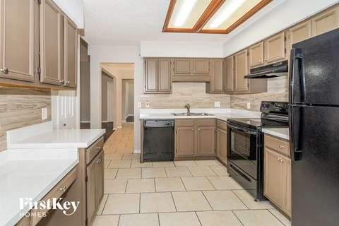 a kitchen with black appliances and white counters and wood cabinets
