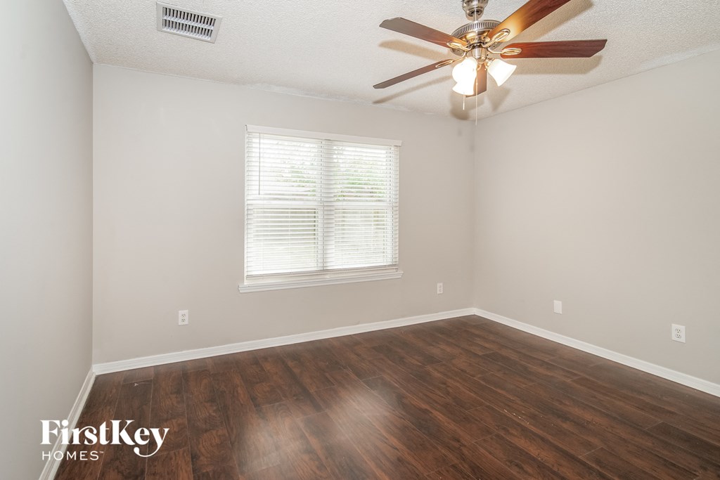 a bedroom with hardwood flooring and a ceiling fan