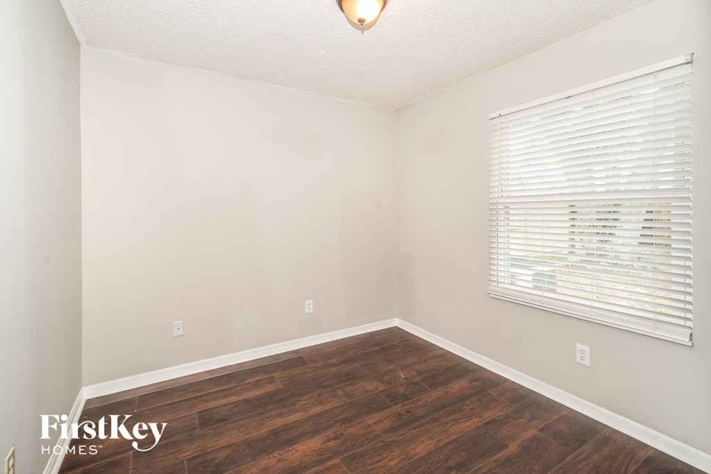 a bedroom with wood flooring and a large window