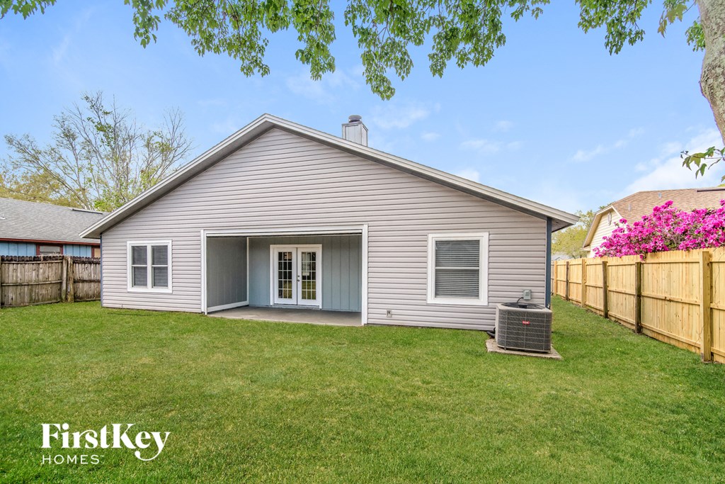 a gray house with a backyard and a barbecue grill