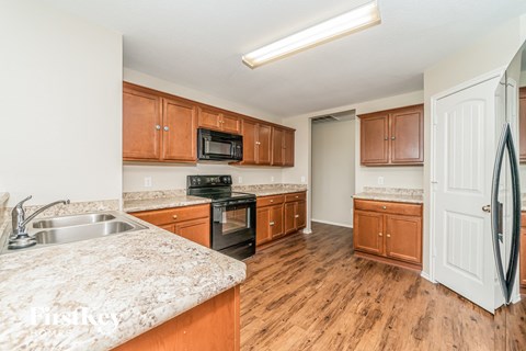 a kitchen with wooden cabinets and granite counter tops and a stainless steel sink