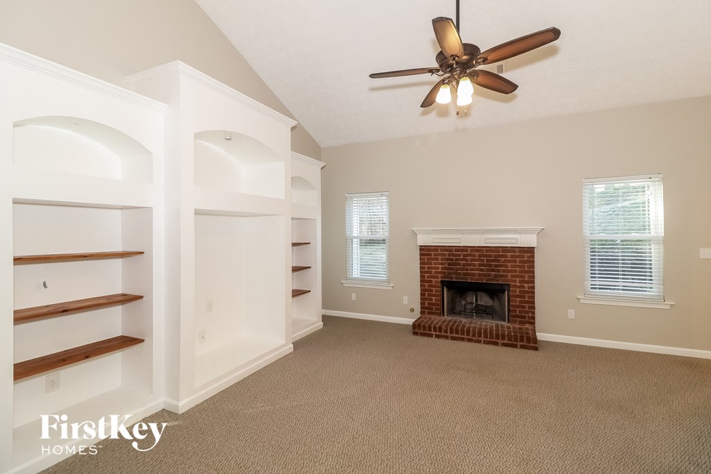 a living room with a brick fireplace and a ceiling fan