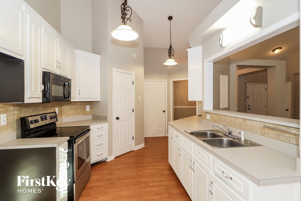 a kitchen with white cabinets and stainless steel appliances and a sink
