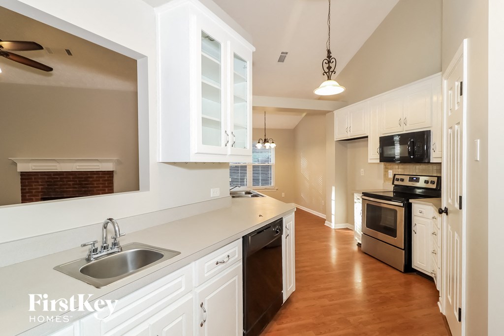 a kitchen with white cabinets and a sink and a window