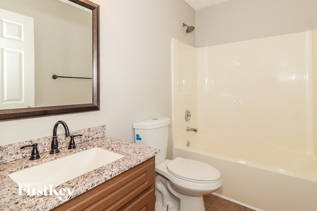 a bathroom with a toilet sink and shower and a mirror