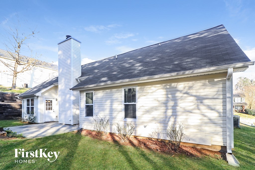 a small white house with a gray roof and a lawn