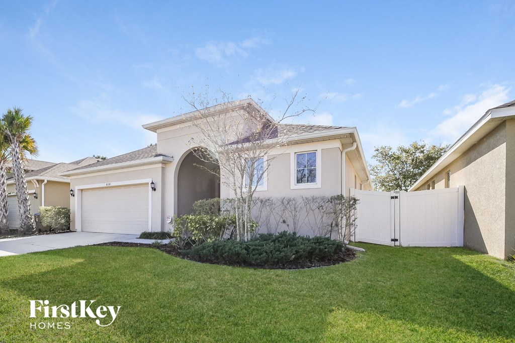 a home with a lawn and a white fence