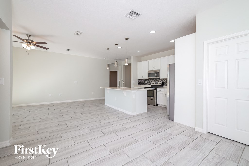 an open kitchen and living room with white tile flooring