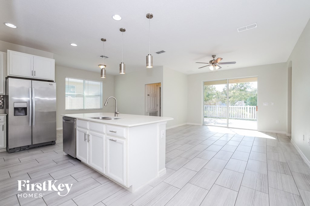 a white kitchen with stainless steel appliances and a white island