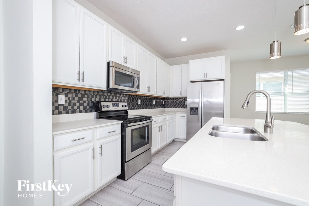 a white kitchen with stainless steel appliances and white cabinets
