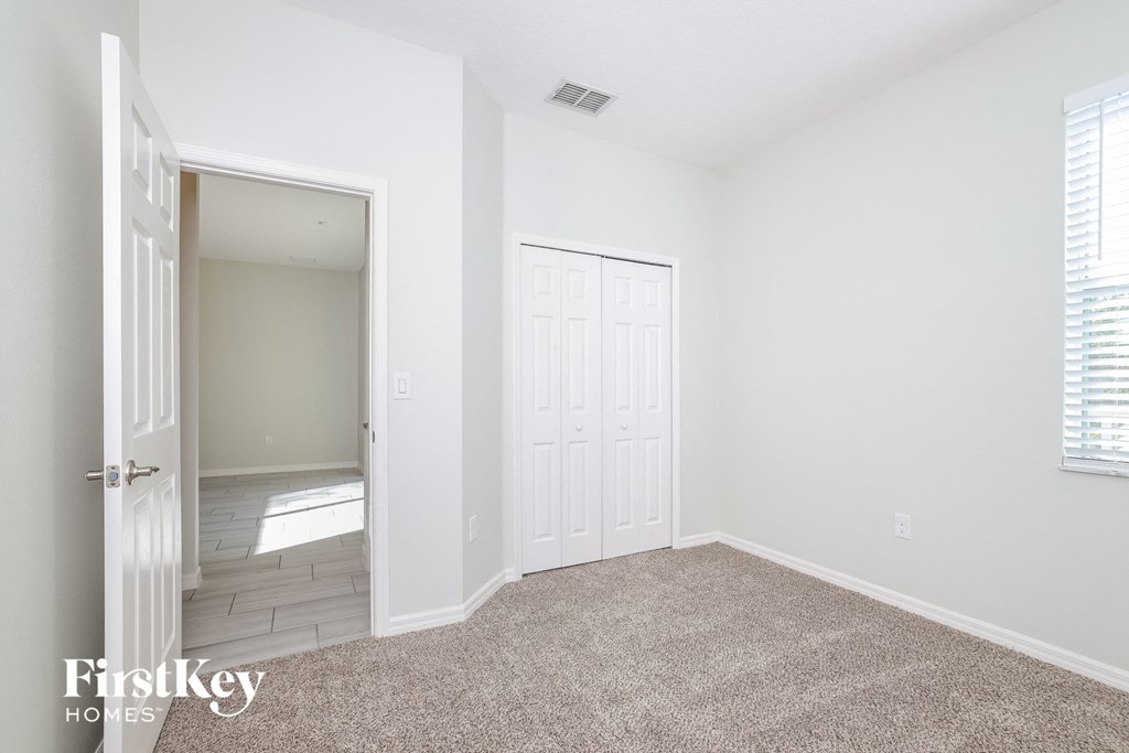 a bedroom with a door to a hallway and a carpeted floor