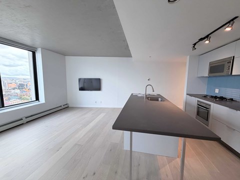 A modern kitchen with a grey countertop and white cabinets.