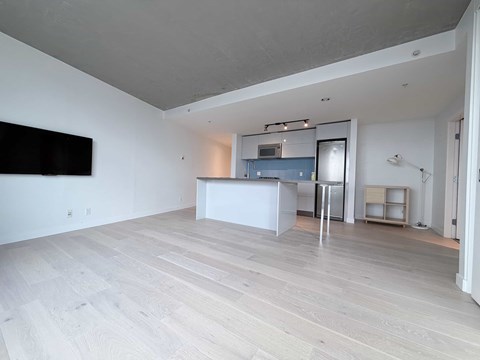 A spacious room with a television on the wall and a bar area.
