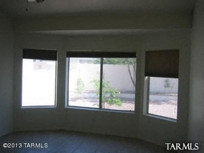 A room with three windows and a view of a street.