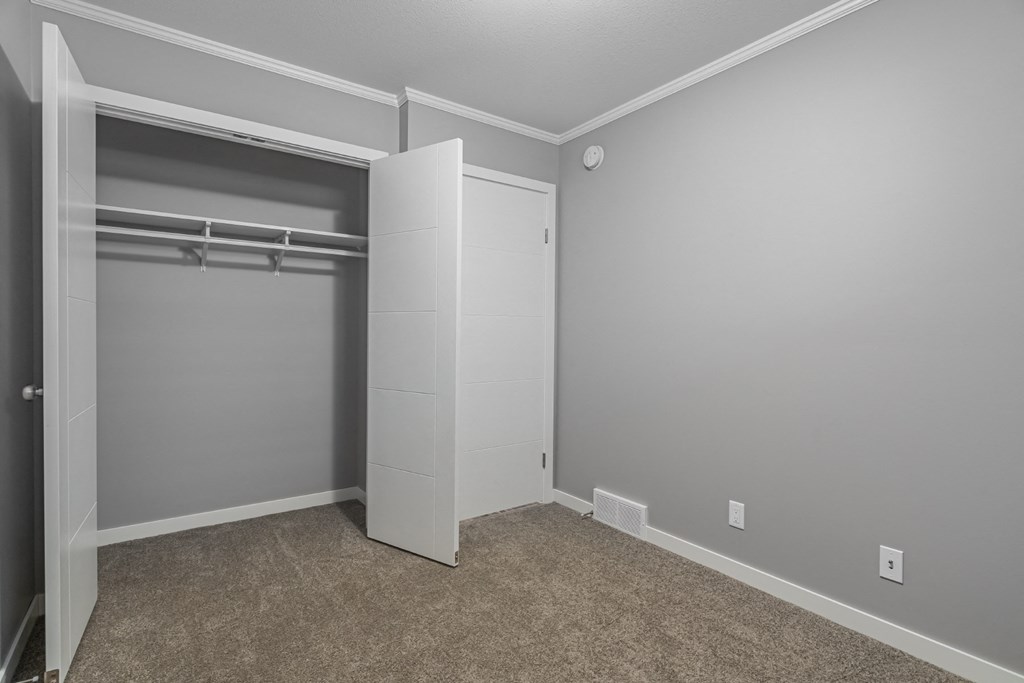 an empty bedroom with a closet and a white closet door