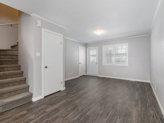the living room and staircase of an empty house with white walls