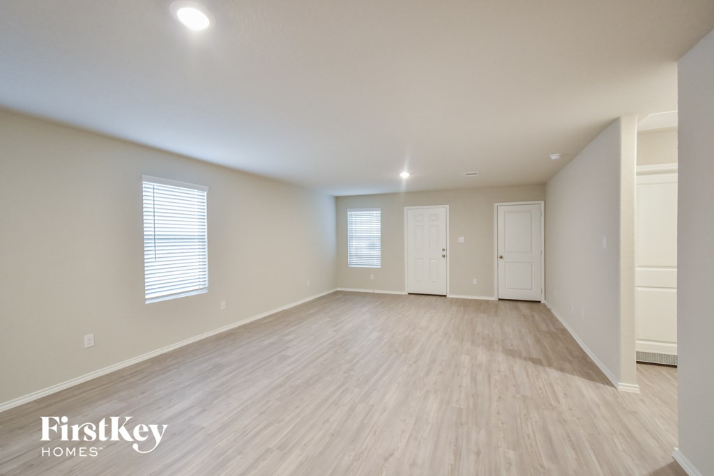 the spacious living room with wood flooring and white walls