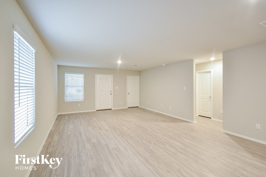 a spacious living room with a hard wood floor and white walls