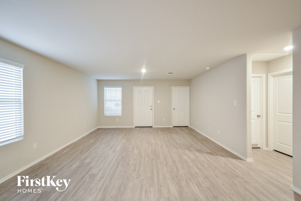 the spacious living room with wood flooring and white walls