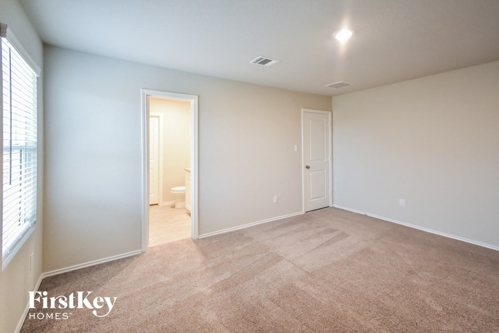 a bedroom with a carpeted floor and a door to a bathroom