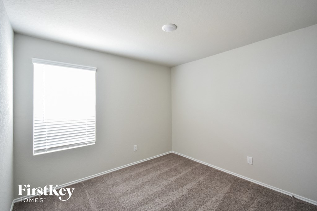 a bedroom with a window and a carpeted floor
