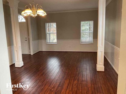 an empty living room with wood floors and a chandelier