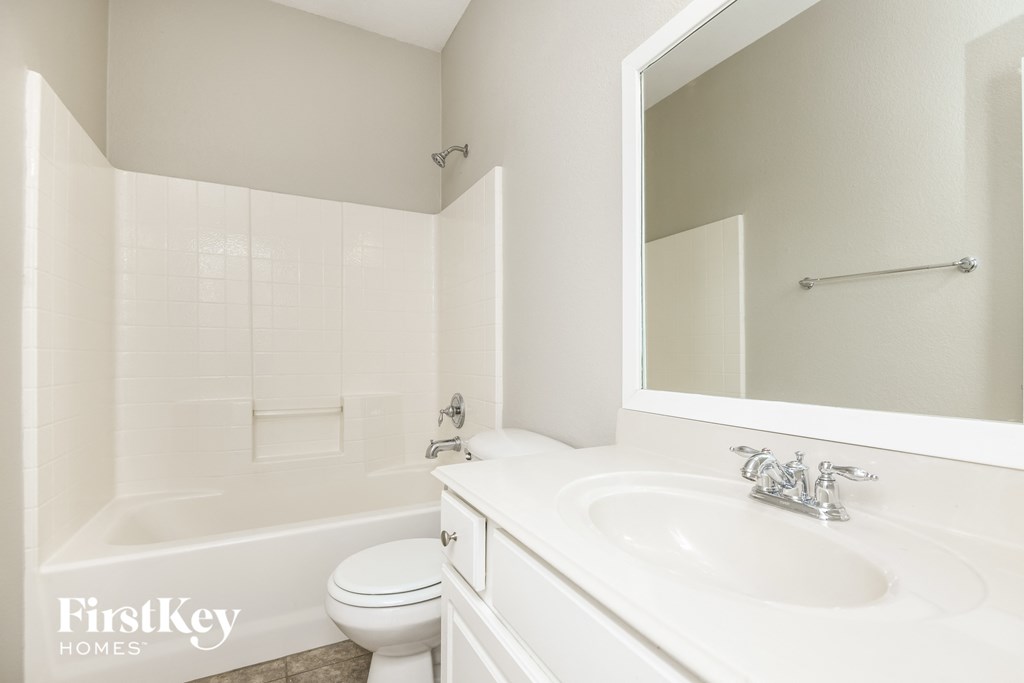 a white bathroom with a white sink and toilet and a mirror