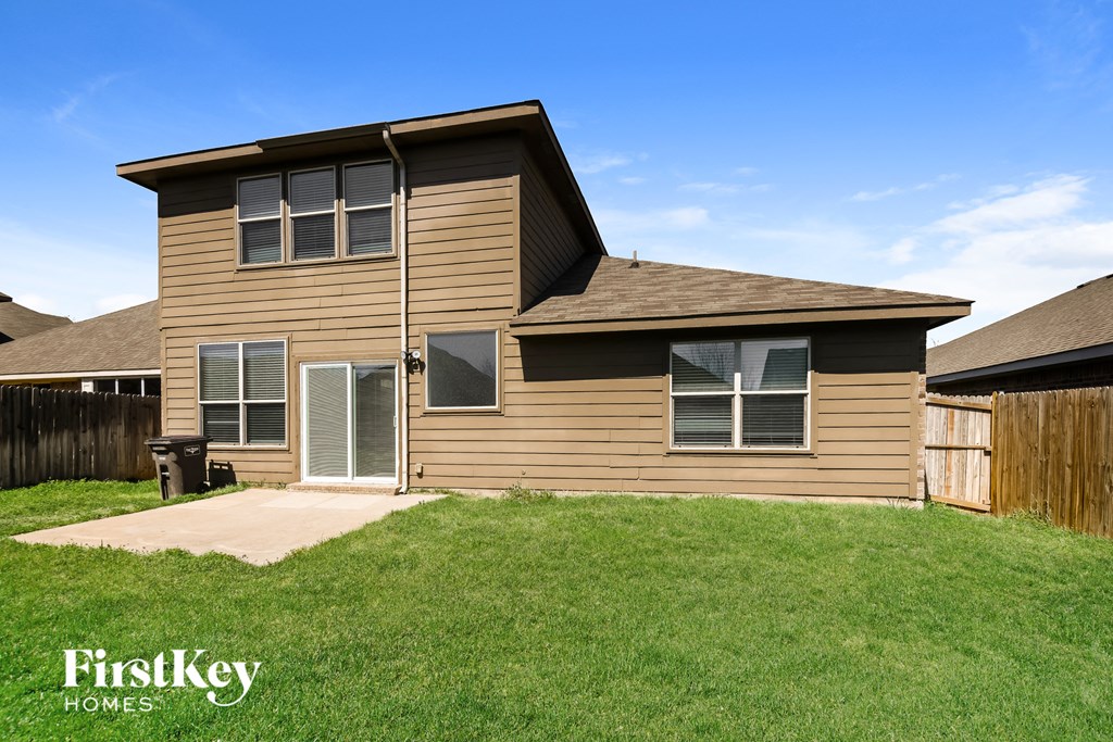 a tan house with a yard and a wooden fence
