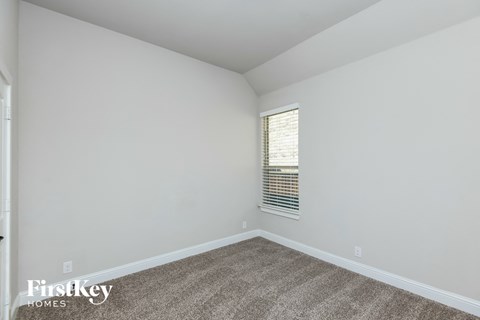 a bedroom with white walls and carpet and a window