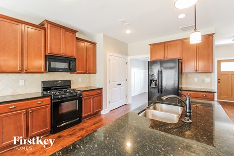 a kitchen with wooden cabinets and black appliances and granite counter tops