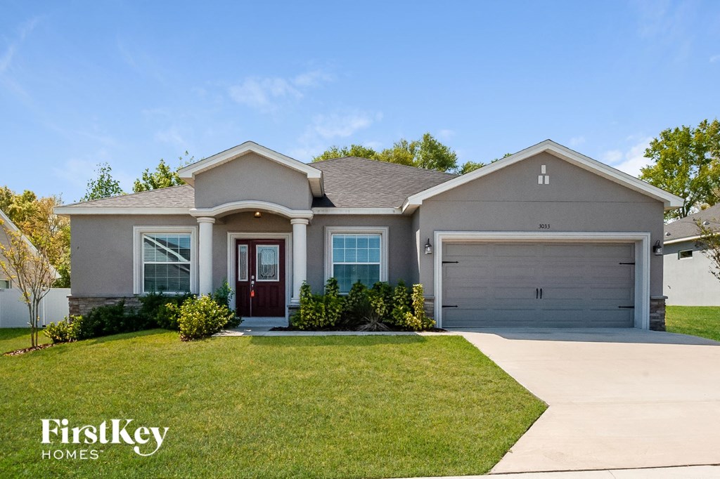 a beige house with a lawn and a garage door