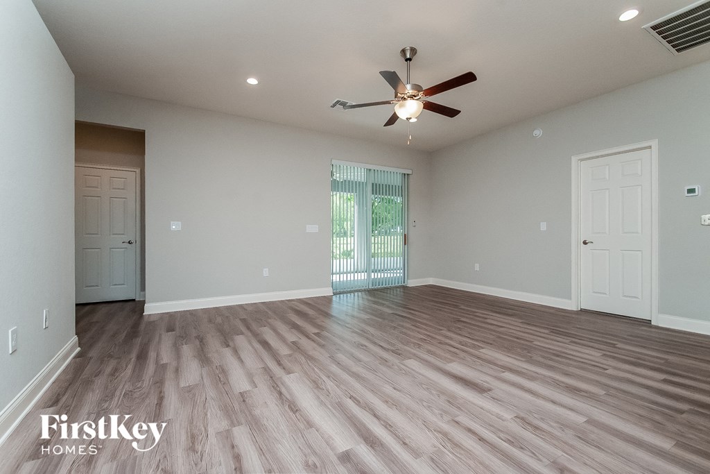 the spacious living room with hardwood floors and a ceiling fan