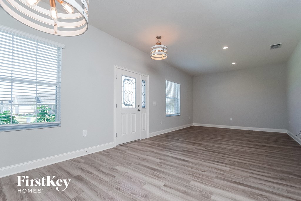 an empty living room with a white door and a window