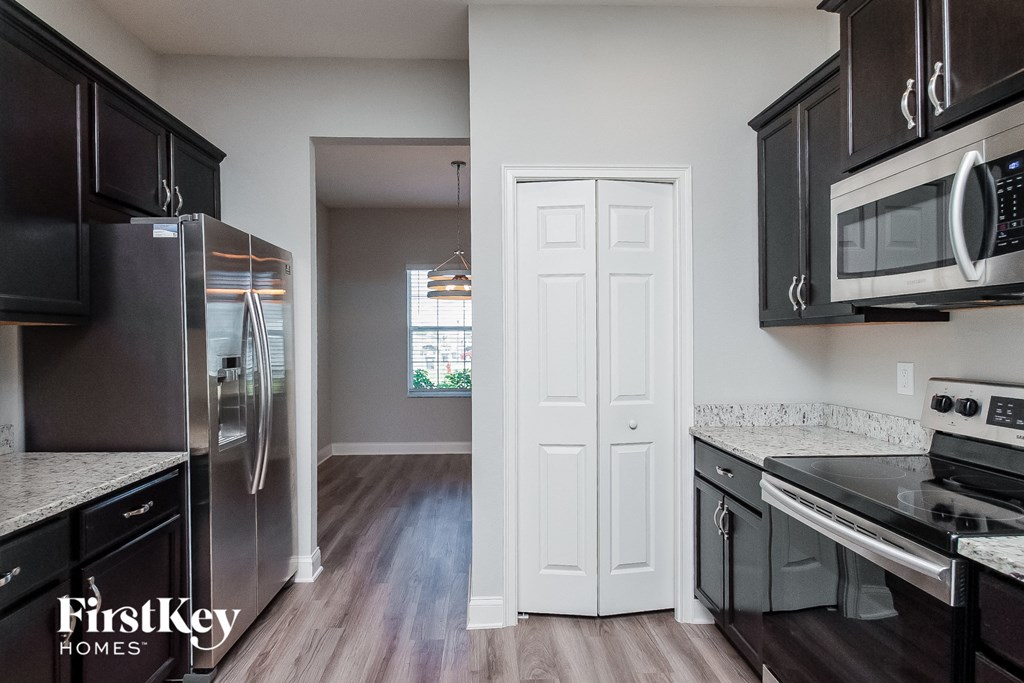 a kitchen with black cabinets and stainless steel appliances and a white door