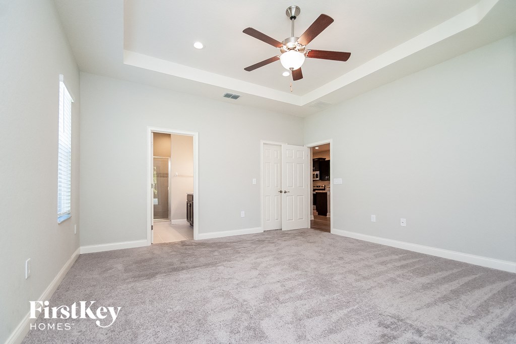 a spacious living room with carpet and a ceiling fan