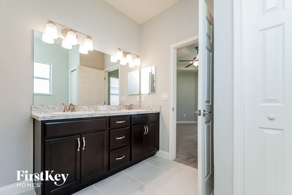 a bathroom with dark cabinets and a large mirror