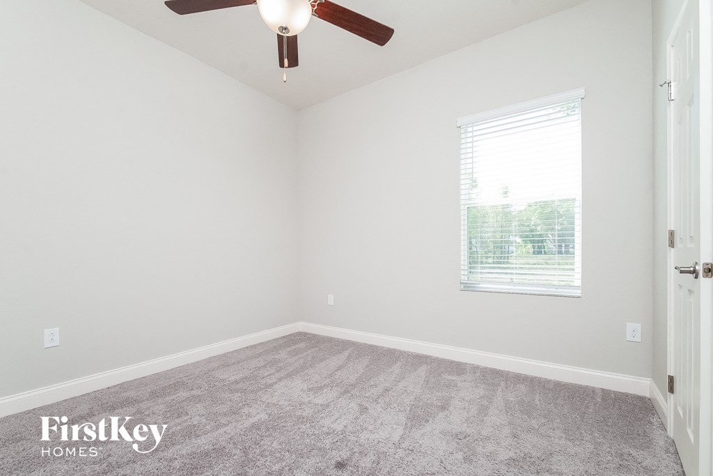 an empty room with a ceiling fan and a window