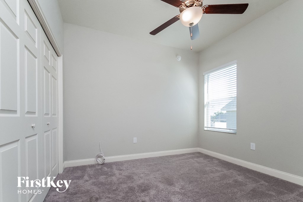 an empty room with a ceiling fan and a window