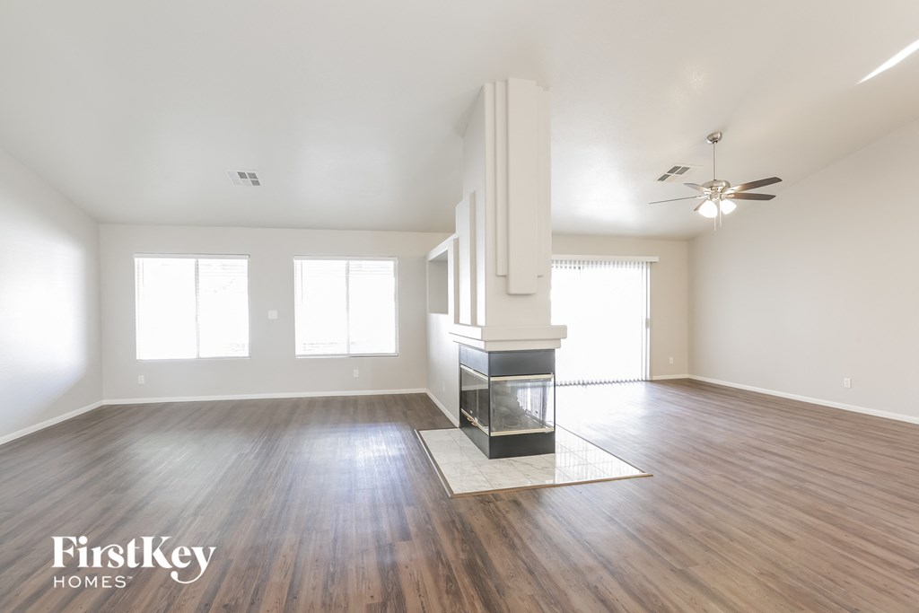 an empty living room with a fireplace and wood flooring