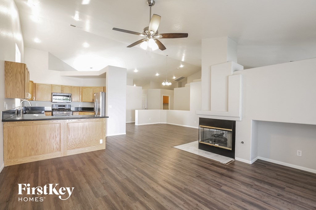 an empty living room with a fireplace and a kitchen