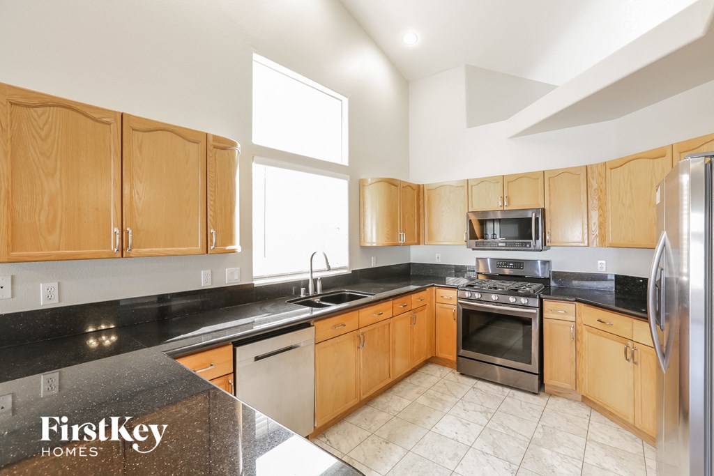 a kitchen with wooden cabinets and stainless steel appliances and black counter tops
