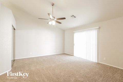 a spacious living room with carpet and a ceiling fan